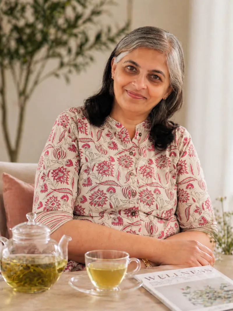 Neena sitting at a café table with herbal tea, smiling warmly
